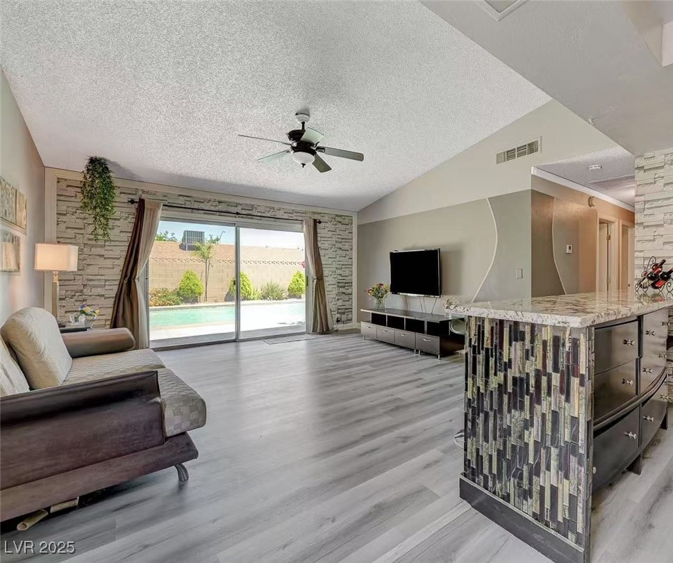 3266 Mountain Spring Road Las Vegas, NV 89146 - Photo 4 of 49 Living area featuring vaulted ceiling, a textured ceiling, ceiling fan, light wood-style flooring, and visible vents