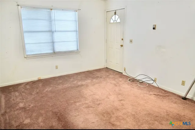 an empty room with cabinet and windows