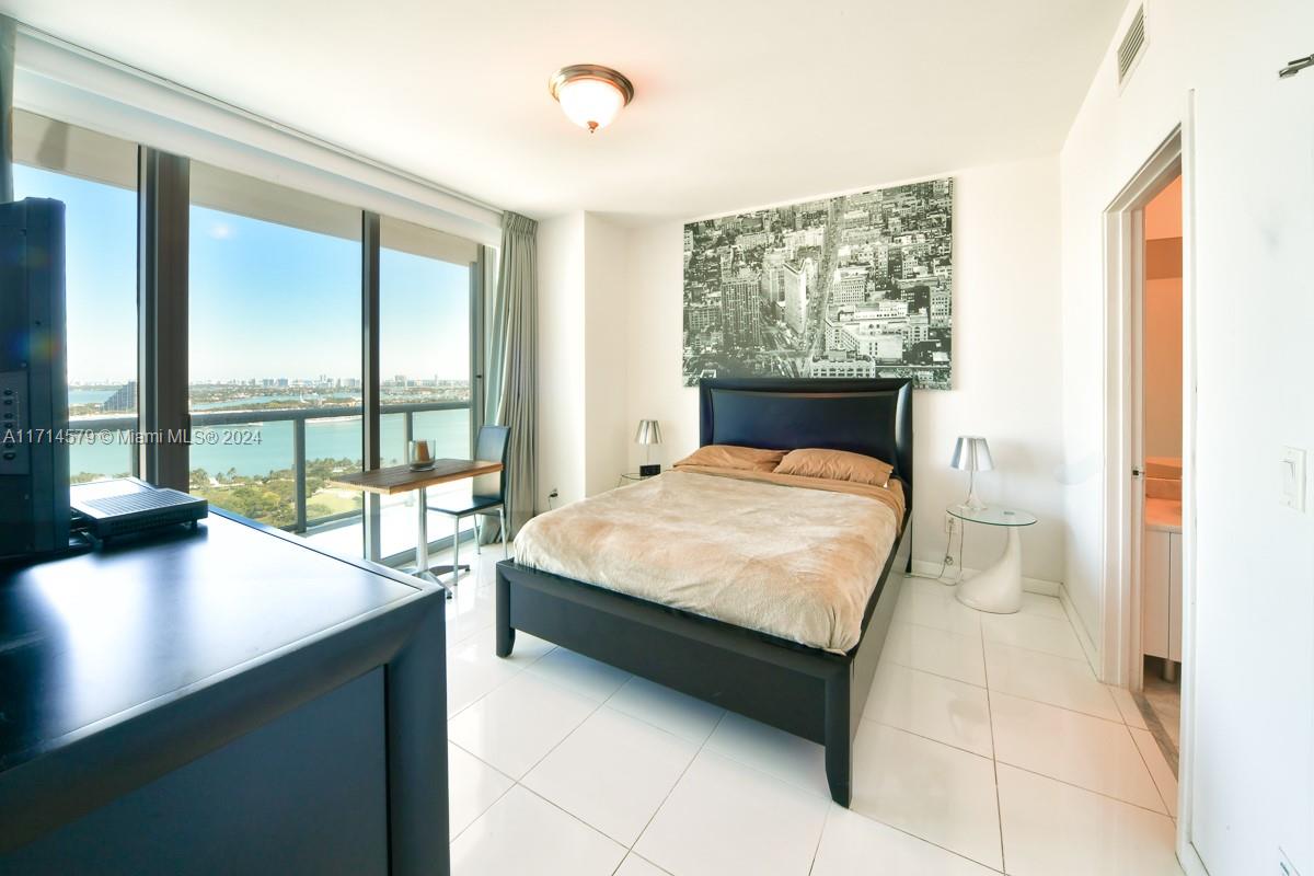 888 Biscayne Boulevard, Unit 2511 Miami, FL 33132 - Photo 6 of 26 a bed sitting in a bedroom next to a window