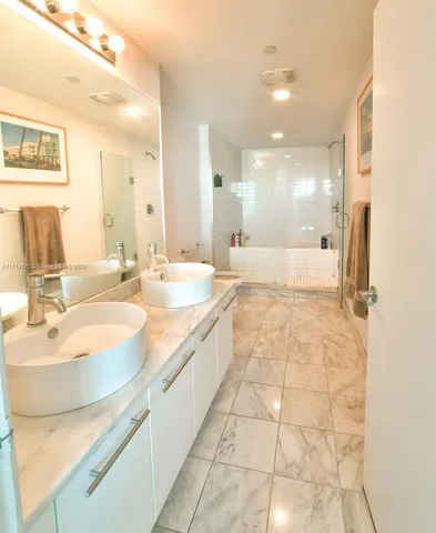 a bathroom with a double vanity sink mirror and shower