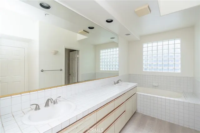 a spacious bathroom with a tub sink and mirror