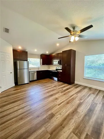 a view of kitchen and empty room with wooden floor