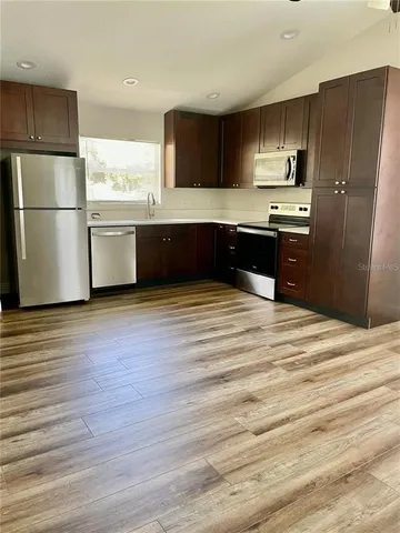 a kitchen with stainless steel appliances wooden floor sink and microwave
