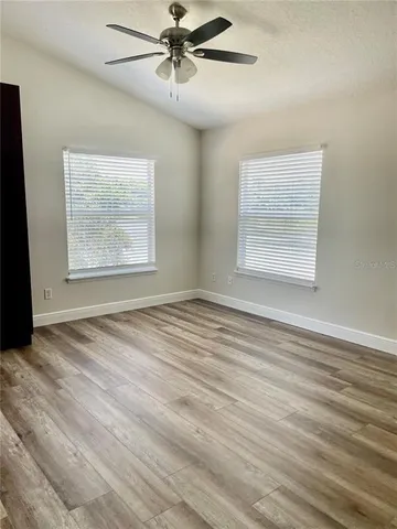 en empty room with wooden floor fan and windows