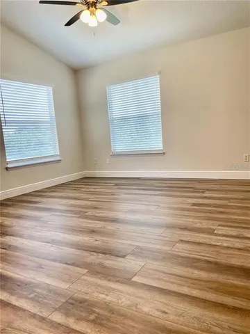 a view of an empty room with window and a chandelier fan