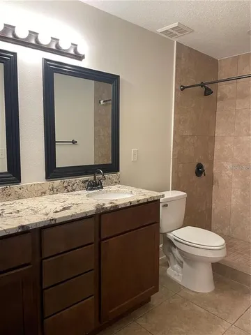 a bathroom with a granite countertop sink toilet and mirror
