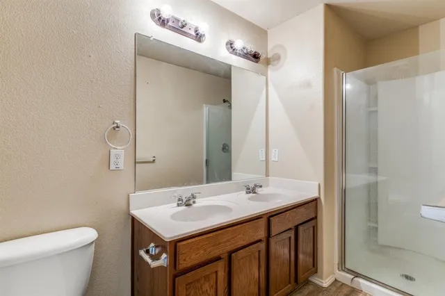 a bathroom with a sink a toilet a mirror and shower