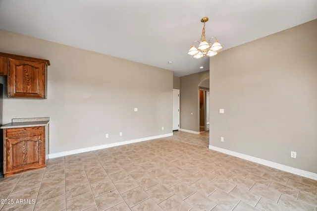 a view of an empty room with chandelier fan