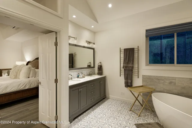 a en suite bathroom with a double vanity sink a mirror and a bathtub