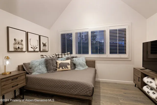 a bedroom with a bed a couch and a flat tv screen on dresser