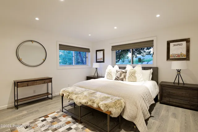 a bedroom with a bed a dresser and potted plant