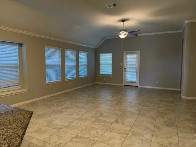 an empty room with chandelier fan and windows