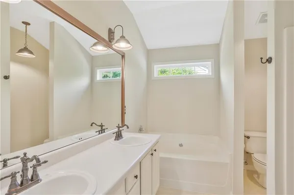 a bathroom with a tub a sink and mirror