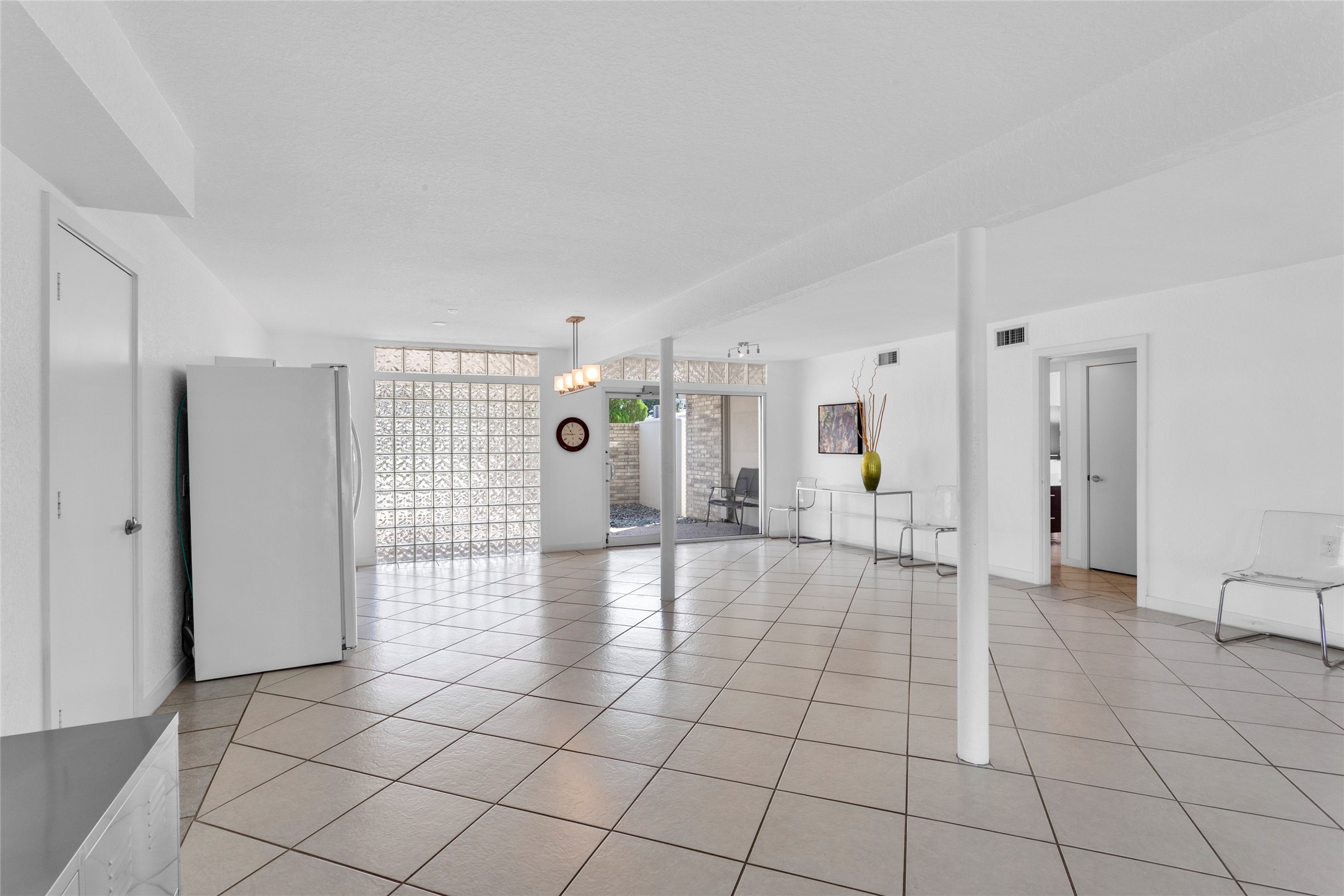 67 Harbor Lane Kemah, TX 77565 - Photo 29 of 47 Another view of this modern, open layout with large tile flooring and ample natural light from glass block windows. It includes sleek, minimalistic decor and direct access to the outdoor areas, offering a versatile space for living and entertaining.