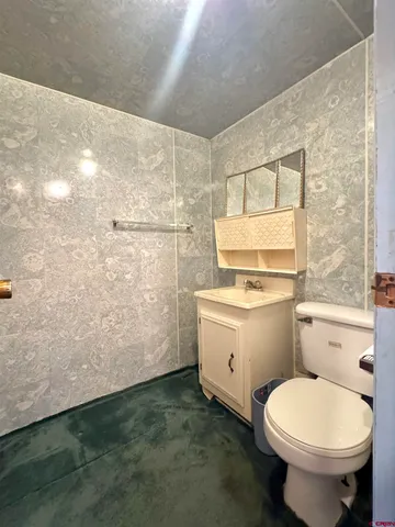a bathroom with a granite countertop toilet a sink and a mirror