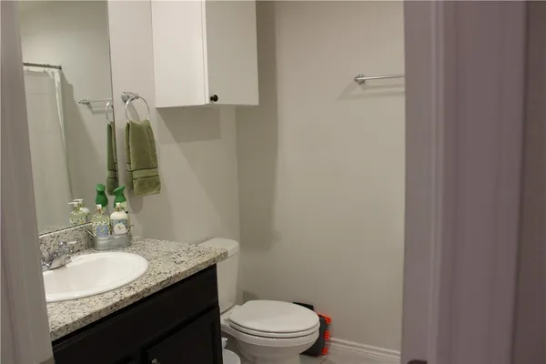 a bathroom with a granite countertop sink toilet and mirror
