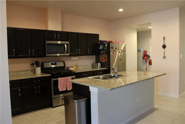 a kitchen with kitchen island granite countertop a sink stainless steel appliances and cabinets