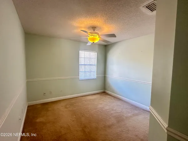 an empty room with a window and a fan
