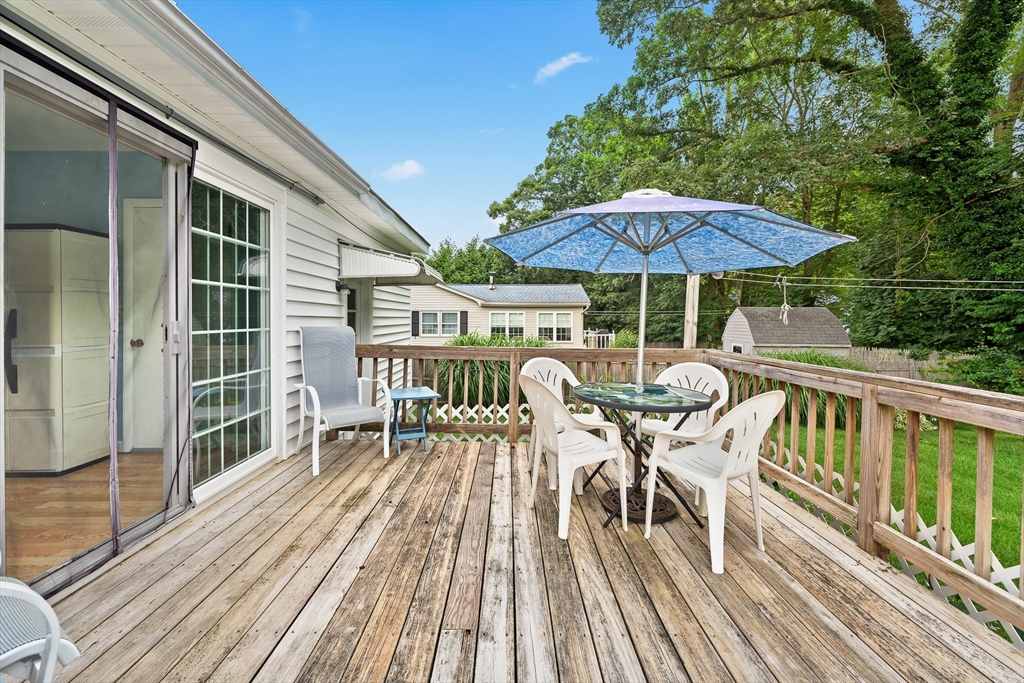 7 Stephen Drive Webster, MA 01570 - Photo 37 of 38 a view of a roof deck with table and chairs under an umbrella with wooden floor