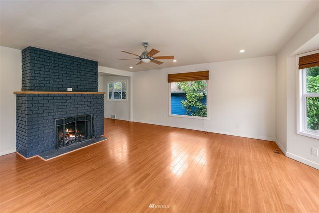 a view of a livingroom with wooden floor a fireplace and windows