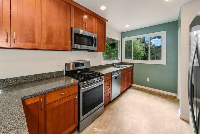 a kitchen with stainless steel appliances granite countertop a stove a sink and a microwave