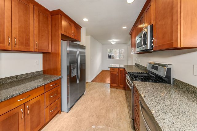 a kitchen with stainless steel appliances granite countertop wooden cabinets a stove top oven a sink and dishwasher