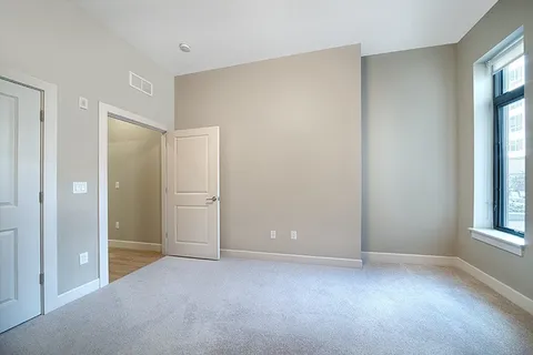 a view of an empty room with windows and closet
