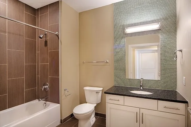 a bathroom with a granite countertop sink a toilet and shower
