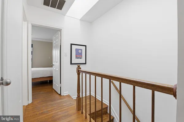 a view of a hallway with wooden floor and a bathroom