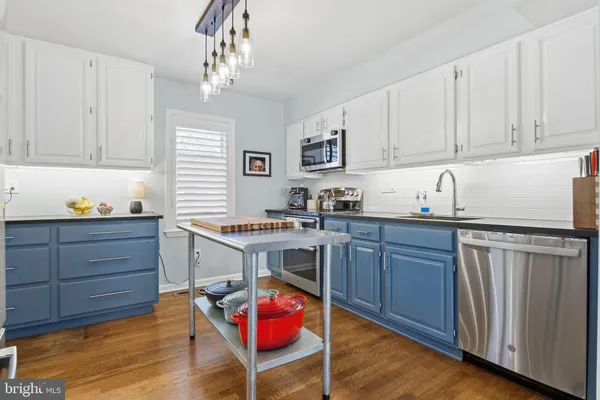 a kitchen with stainless steel appliances granite countertop a sink dishwasher and cabinets with wooden floor