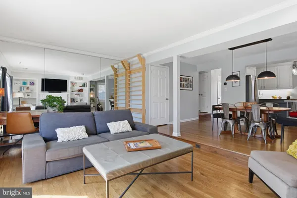 a living room with furniture kitchen view and a wooden floor