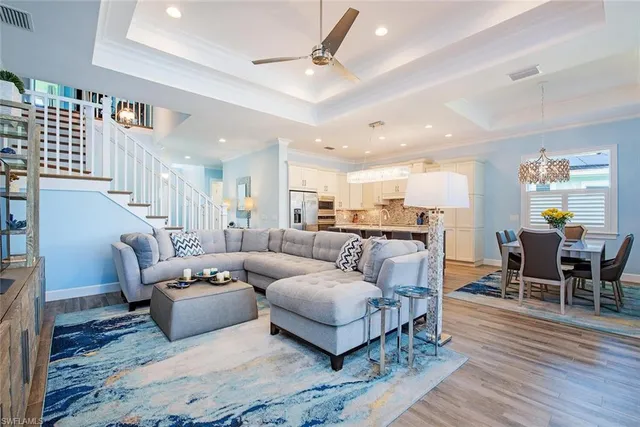 a living room with furniture kitchen view and a wooden floor