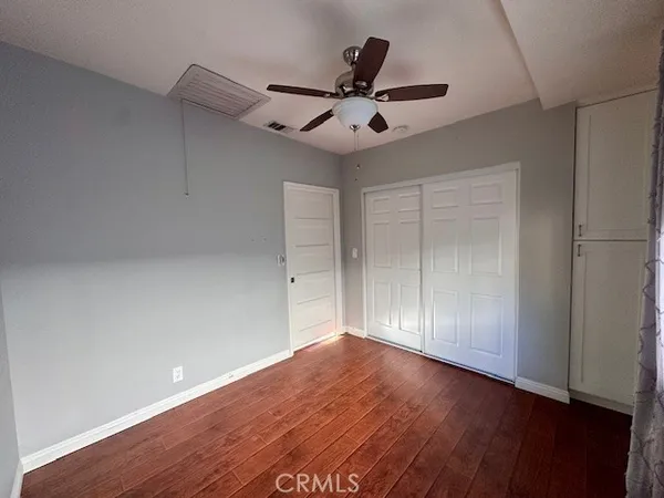 an empty room with wooden floor ceiling fan and windows