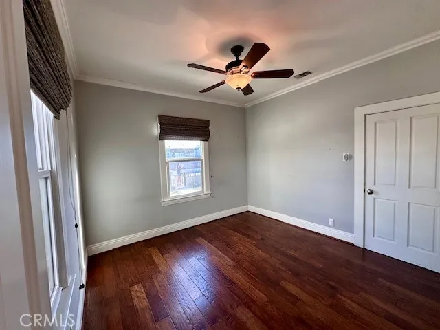 an empty room with wooden floor fan and windows