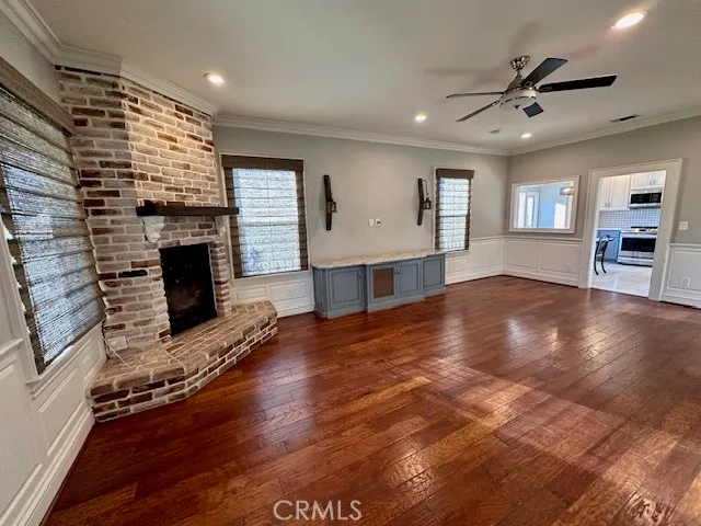 an empty room with wooden floor fireplace and windows