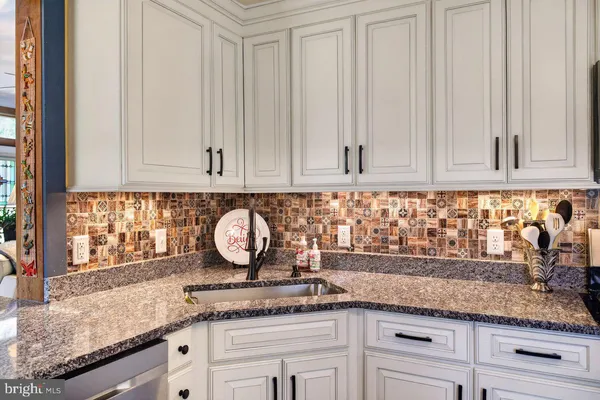 a kitchen with granite countertop stainless steel appliances white cabinets and a sink
