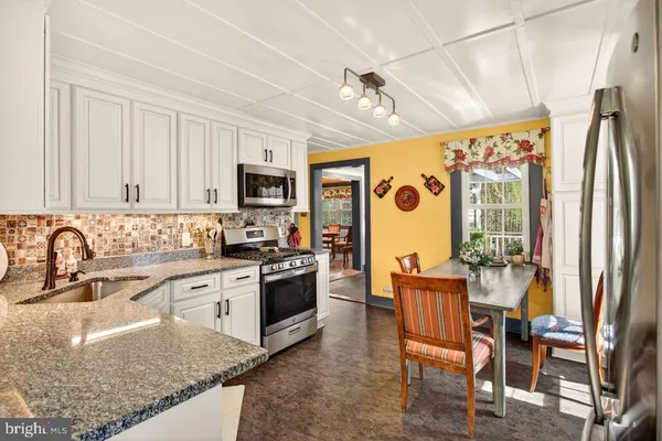 a large kitchen with stainless steel appliances granite countertop a stove a sink dishwasher a dining table and chairs with wooden floor