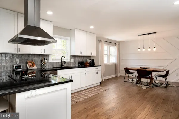 a kitchen with stainless steel appliances a table a stove a refrigerator a microwave a dining table and chairs with wooden floor