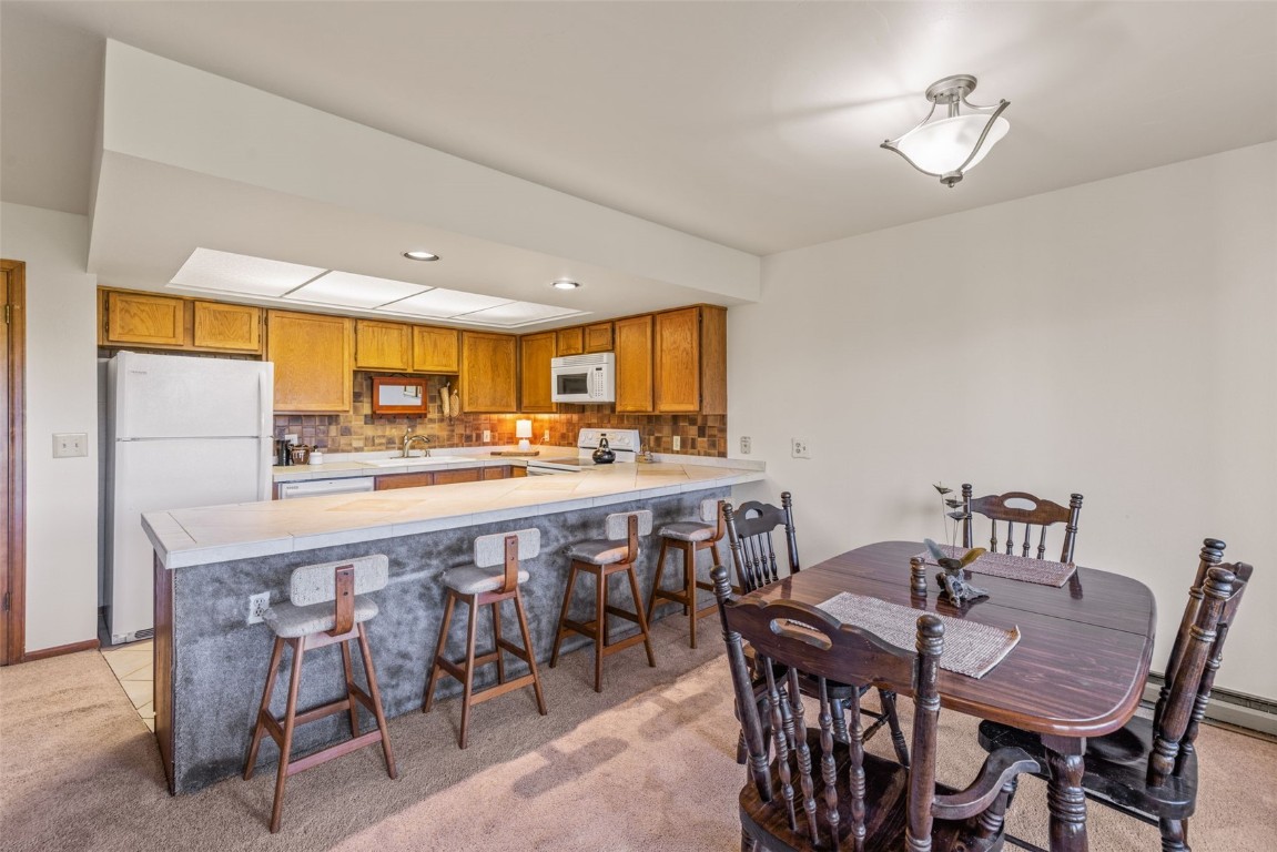 4624 Ryan Gulch Road, Unit 4624 Silverthorne, CO 80498 - Photo 9 of 31 a dining hall with stainless steel appliances a dining table and chairs with wooden floor