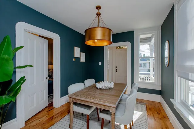 a kitchen with stainless steel appliances granite countertop a stove a refrigerator a sink a dining table and chairs with wooden floor