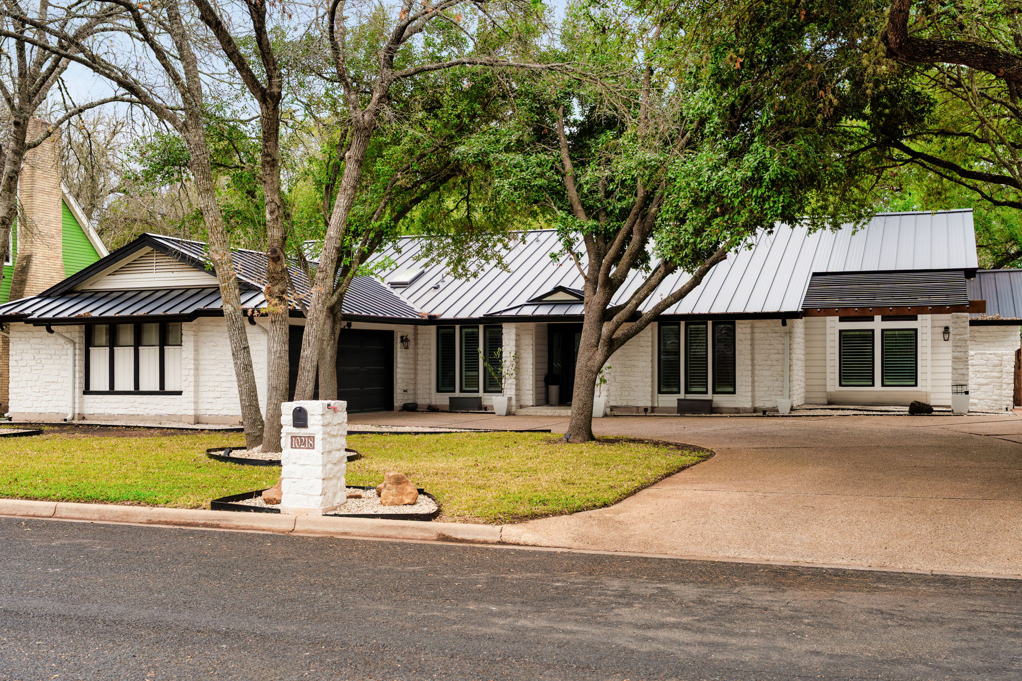 a front view of a house with a garden and tree