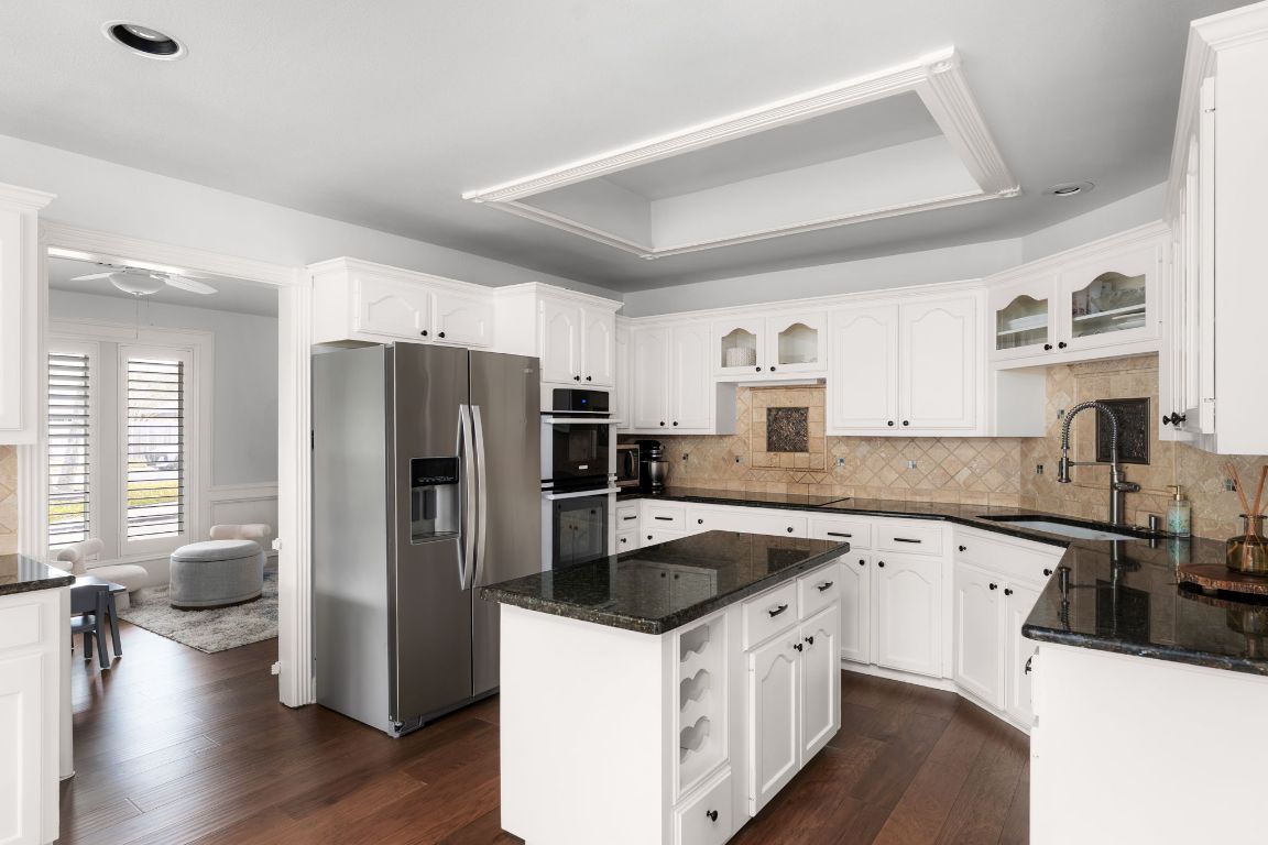 10218 Braemar Drive Austin, TX 78747 - Photo 12 of 34 Kitchen featuring stainless steel appliances, dark stone countertops, glass insert cabinets, and decorative backsplash