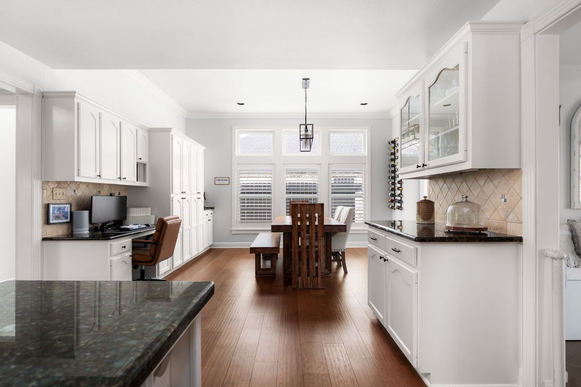 10218 Braemar Drive Austin, TX 78747 - Photo 13 of 34 Kitchen featuring tasteful backsplash, dark stone countertops, white cabinets, built in study area, and ornamental molding