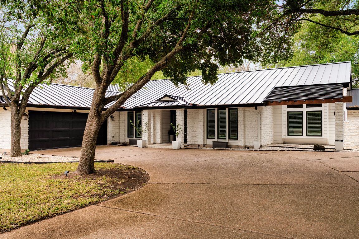 10218 Braemar Drive Austin, TX 78747 - Photo 2 of 34 View of front of property featuring a standing seam roof, brick siding, a metal roof, and driveway