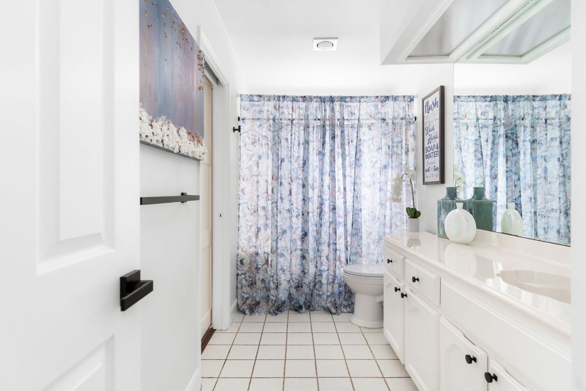 10218 Braemar Drive Austin, TX 78747 - Photo 24 of 34 Full bath featuring curtained shower, vanity, and light tile patterned floors