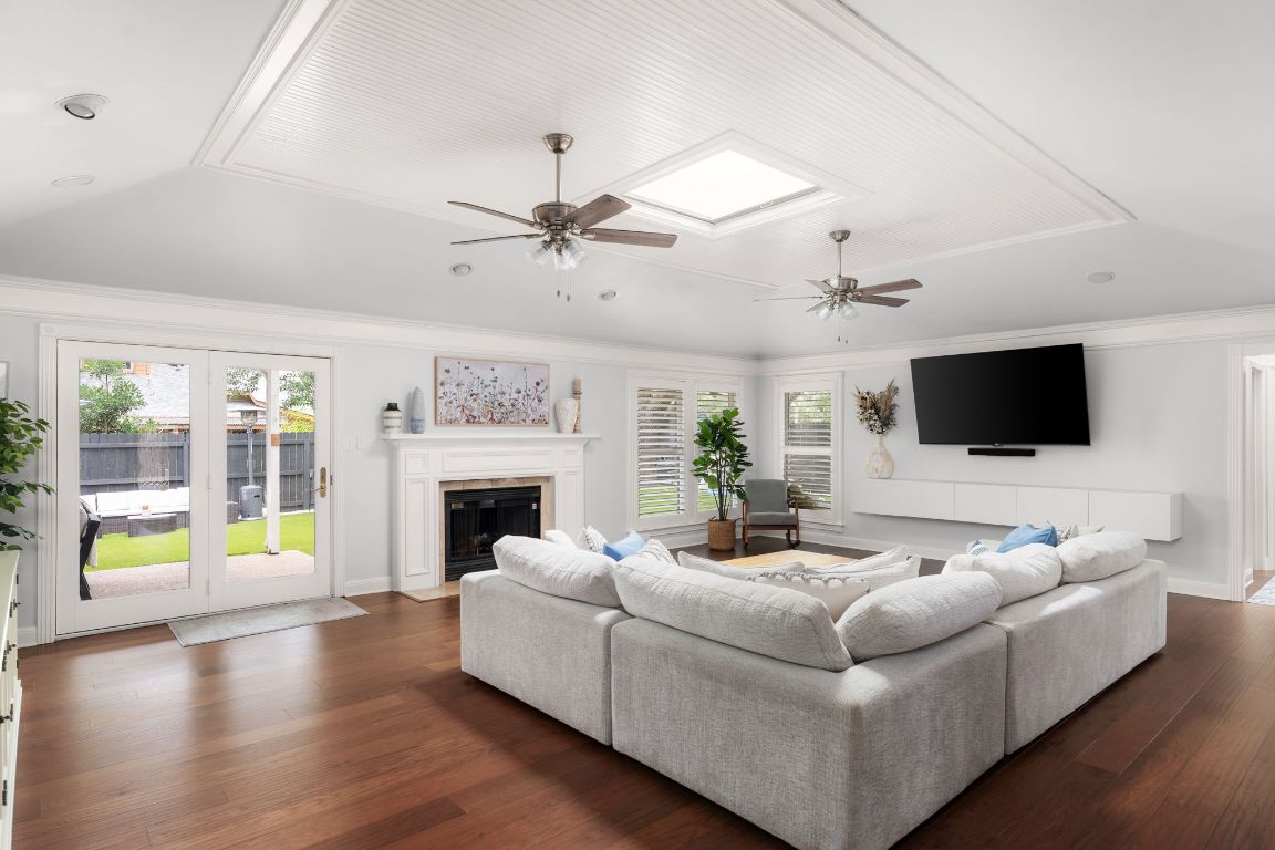 10218 Braemar Drive Austin, TX 78747 - Photo 7 of 34 Living room with ornamental molding, a fireplace with flush hearth, dark wood finished floors, lofted ceiling, and a ceiling fan