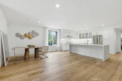 a kitchen with stainless steel appliances a sink a stove a refrigerator and white cabinets