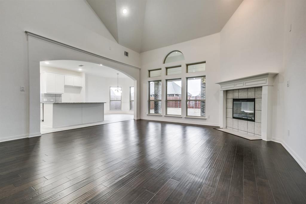 104 Sweetleaf Drive Red Oak, TX 75154 - Photo 11 of 36 This spacious living area features dark wood flooring, high vaulted ceilings, and a fireplace with a white mantel and tile surround