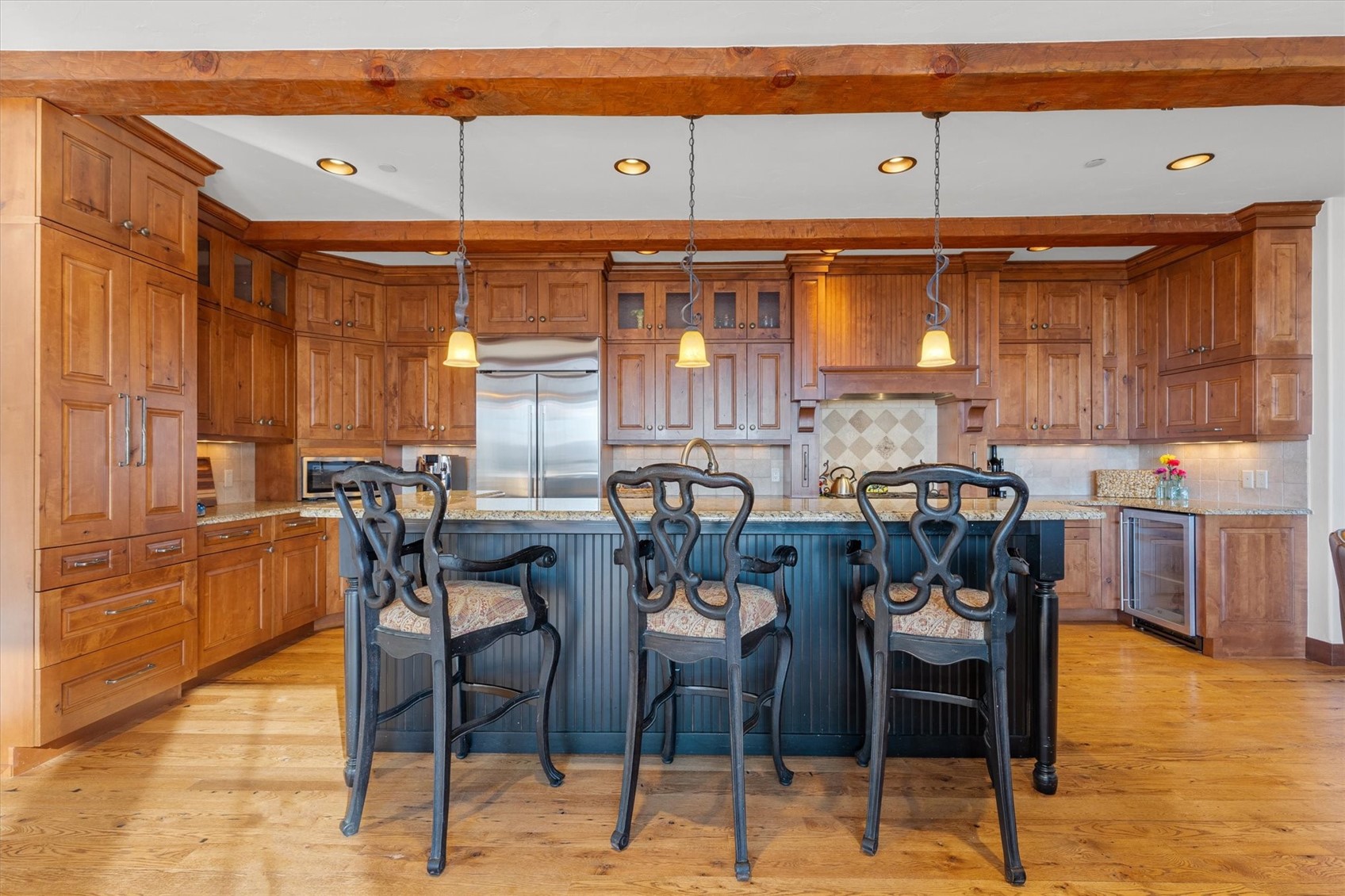2324 Glacier Ridge, Unit B Steamboat Springs, CO 80487 - Photo 11 of 46 Kitchen with a kitchen breakfast bar, brown cabinets, light stone counters, hanging light fixtures, and light wood-type flooring