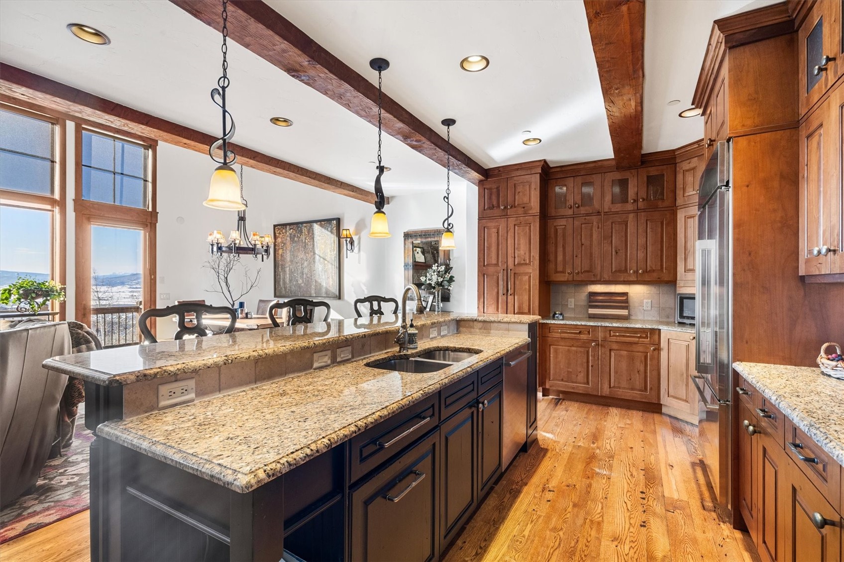 2324 Glacier Ridge, Unit B Steamboat Springs, CO 80487 - Photo 6 of 46 Kitchen featuring light stone counters, hanging light fixtures, a breakfast bar area, light wood-type flooring, and beamed ceiling